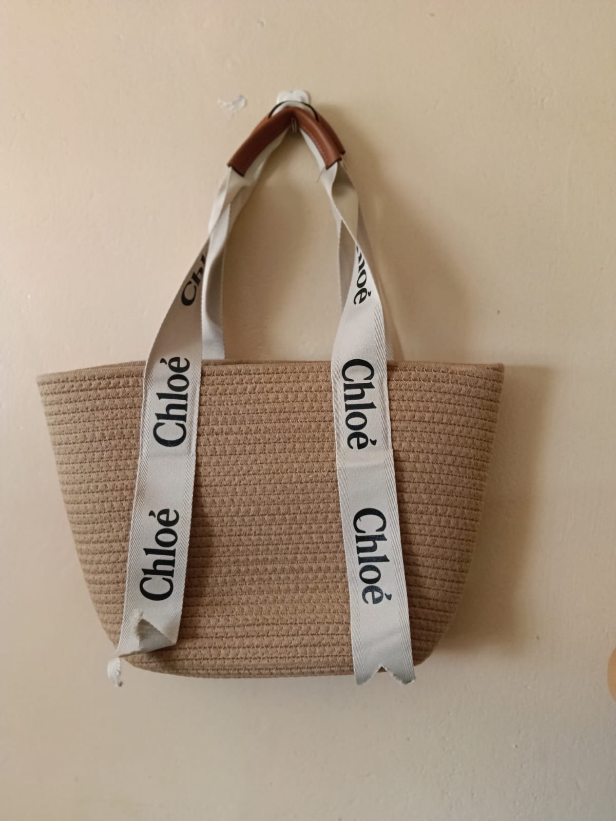 Natural Ribbon-Handle Tote — A natural woven tote finished with long printed ribbon handles and a compact leather hand grip.