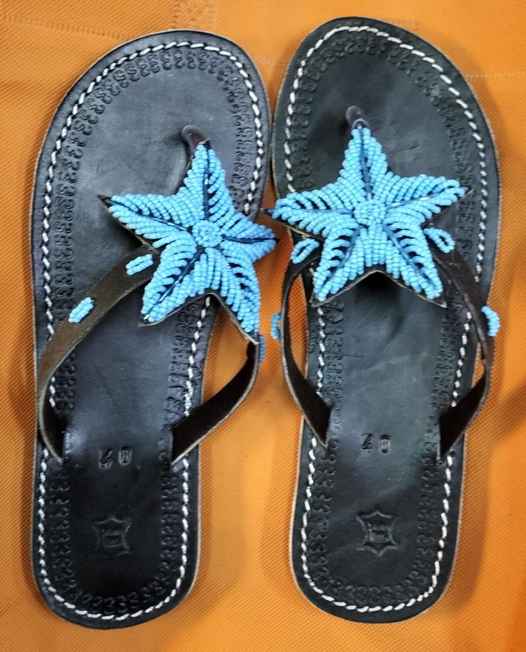 Sky-Blue Beaded Star Leather Sandals — Dark leather flip-flop sandals finished with a raised sky-blue beaded star and white saddle stitching around the sole.