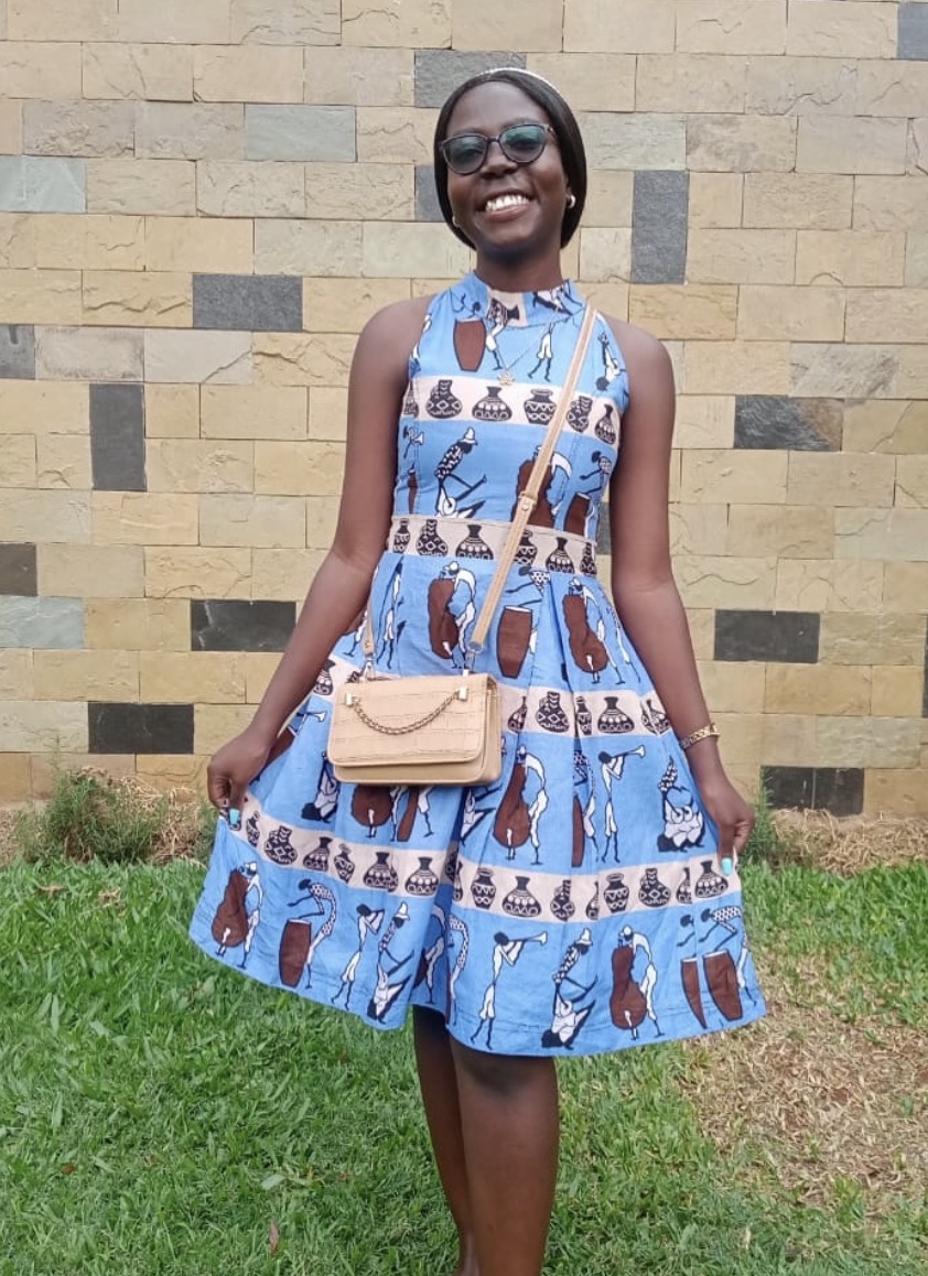 Blue Figure-Print Halter Dress — A sleeveless halter-neck fit-and-flare dress in a sky-blue print of figures and clay pots, banded with a contrast motif stripe.